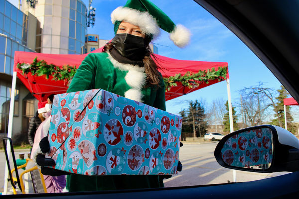 Holiday elf giving present through drivers window