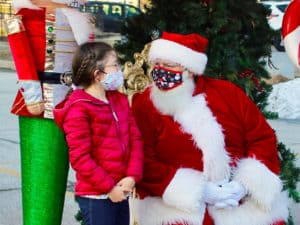 Masked girl talking to masked Santa
