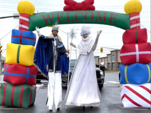 Stilt walkers under a large iinflated welcome arch of presents